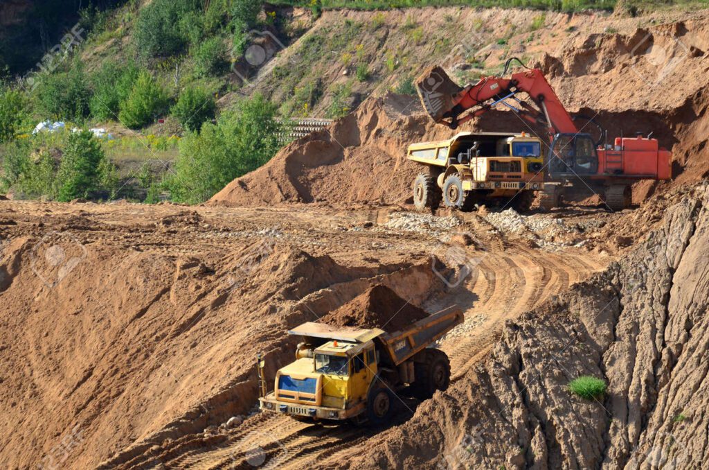 136067812-excavadora-desarrollando-la-arena-a-cielo-abierto-y-cargandola-en-el-camion-volquete-pesado